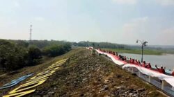 Para pegawai Disparbud Lamongan bersama warga membentangkan bendera merah putih di waduk Gondang Kecamatan Sugio Kabupaten Lamongan/Foto: Muhamat Sapii/Kanaltujuh.com