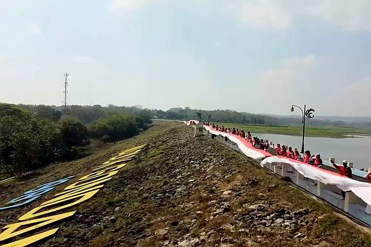 Para pegawai Disparbud Lamongan bersama warga membentangkan bendera merah putih di waduk Gondang Kecamatan Sugio Kabupaten Lamongan/Foto: Muhamat Sapii/Kanaltujuh.com